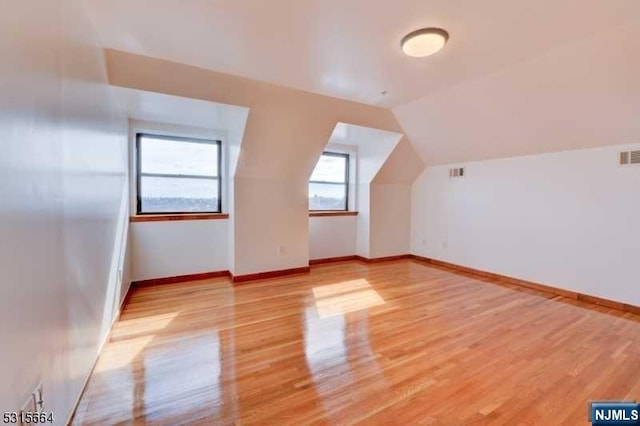 additional living space with light hardwood / wood-style floors and lofted ceiling