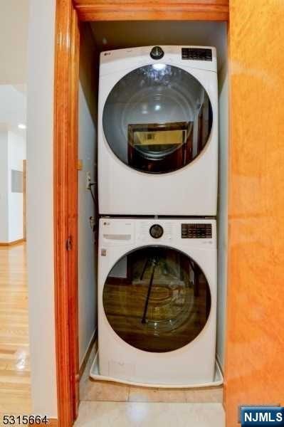 laundry area with hardwood / wood-style flooring and stacked washer and clothes dryer