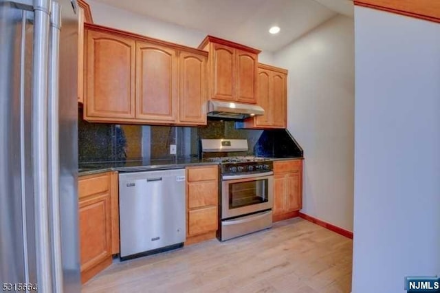 kitchen featuring lofted ceiling, light wood-type flooring, appliances with stainless steel finishes, and tasteful backsplash