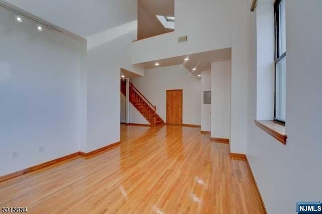 unfurnished room with high vaulted ceiling and light hardwood / wood-style flooring