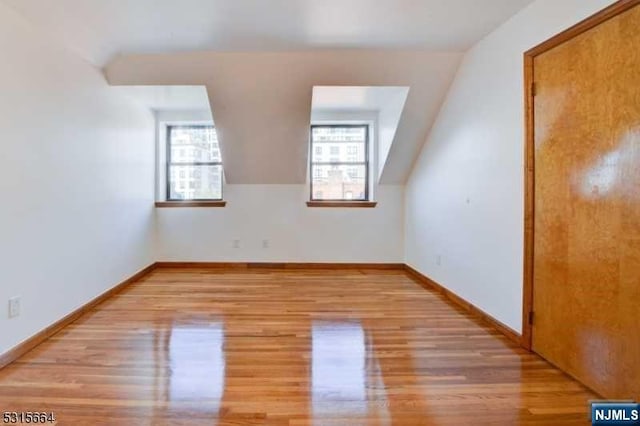 bonus room with vaulted ceiling and light wood-type flooring