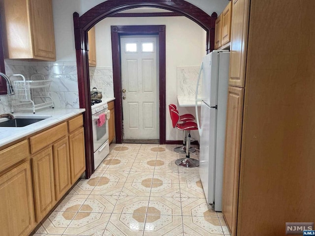 kitchen with white appliances, sink, light tile patterned floors, and tasteful backsplash