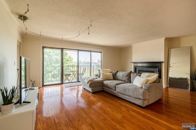 living room featuring crown molding, wood-type flooring, and a textured ceiling