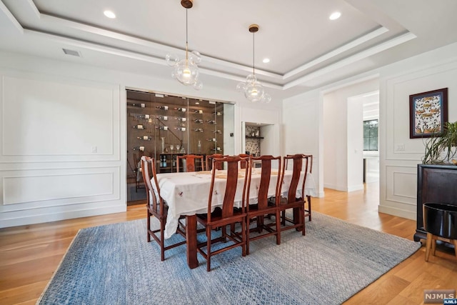 dining space with a tray ceiling and light wood-type flooring