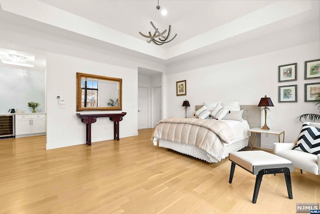 bedroom featuring wine cooler, light hardwood / wood-style flooring, and an inviting chandelier