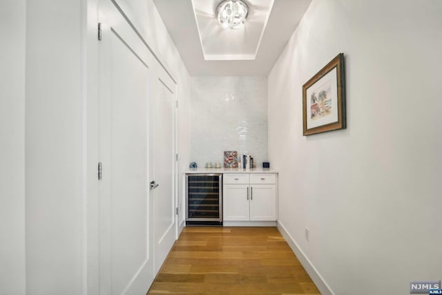 bar with light hardwood / wood-style floors, white cabinetry, and beverage cooler