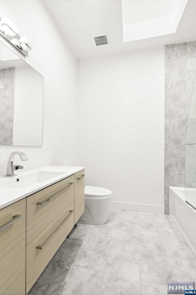 full bathroom featuring a skylight, vanity, bathtub / shower combination, and toilet