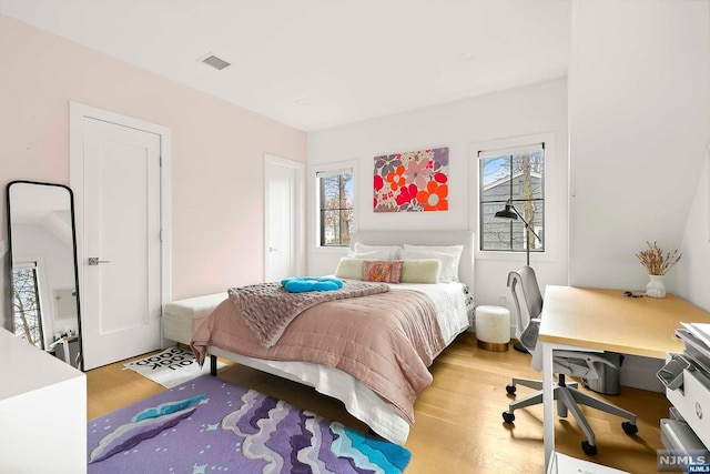 bedroom with wood-type flooring and multiple windows