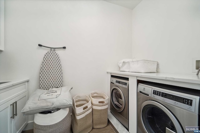 laundry area featuring washer and dryer, hardwood / wood-style floors, and cabinets