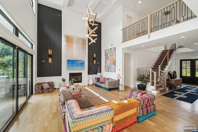 living room featuring french doors, a towering ceiling, hardwood / wood-style flooring, and beam ceiling