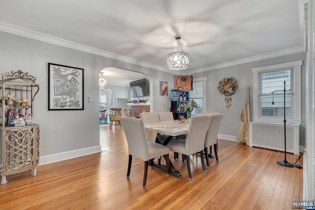 dining room featuring radiator heating unit, an inviting chandelier, light hardwood / wood-style flooring, and crown molding