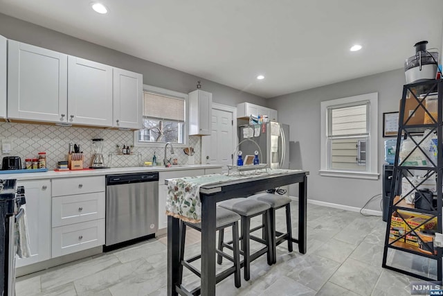 kitchen with sink, white cabinetry, stainless steel appliances, and tasteful backsplash