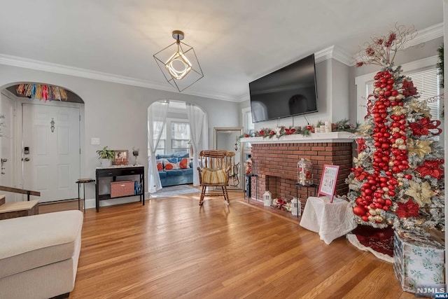 living room with a fireplace, crown molding, and light hardwood / wood-style flooring