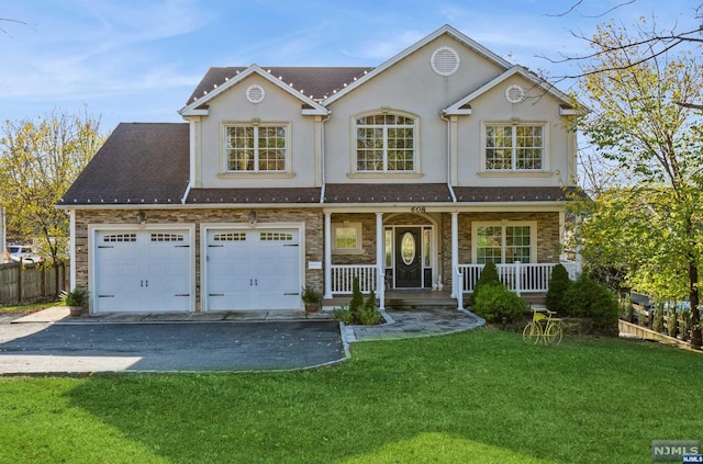 view of front of home featuring covered porch, a garage, and a front lawn