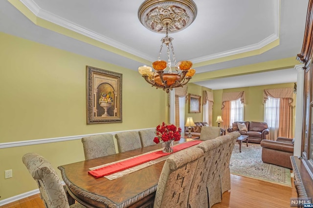 dining room with light wood-type flooring, an inviting chandelier, and crown molding