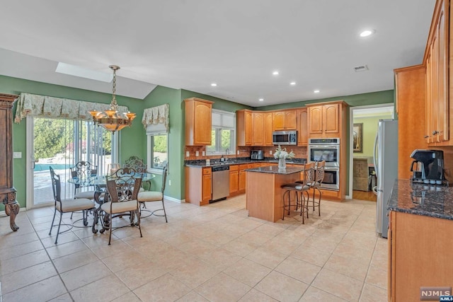 kitchen featuring appliances with stainless steel finishes, a kitchen island, plenty of natural light, and dark stone countertops