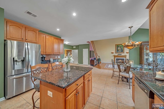 kitchen featuring hanging light fixtures, stainless steel appliances, a kitchen breakfast bar, lofted ceiling, and light tile patterned floors