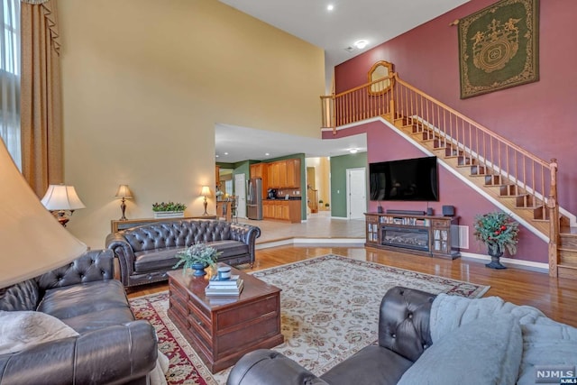 living room featuring a towering ceiling and light wood-type flooring