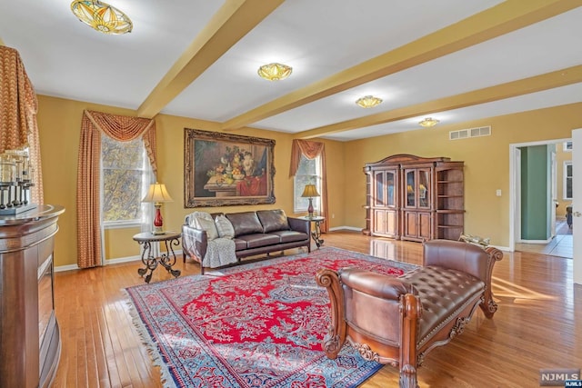 living area with beamed ceiling and light hardwood / wood-style floors