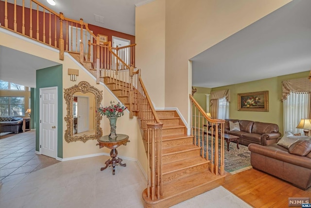 stairway featuring wood-type flooring and a high ceiling