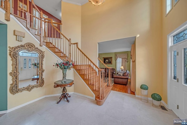 entrance foyer featuring crown molding, plenty of natural light, and a towering ceiling