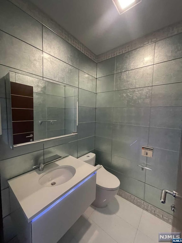 bathroom with tile patterned flooring, vanity, tile walls, and toilet