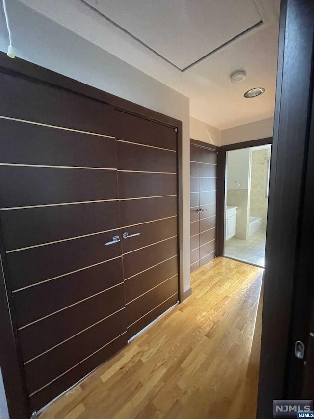 hallway featuring wood-type flooring and tile walls