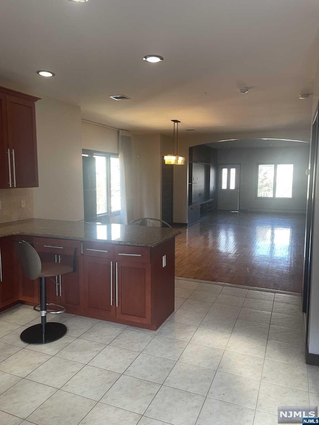 kitchen with decorative light fixtures, light hardwood / wood-style floors, a kitchen breakfast bar, and a healthy amount of sunlight