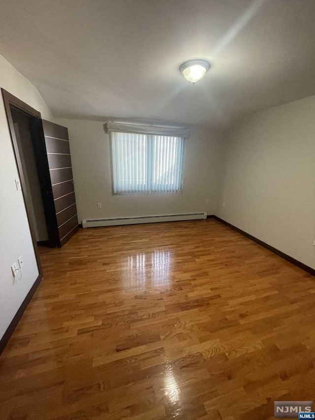 unfurnished bedroom with hardwood / wood-style floors and a baseboard radiator