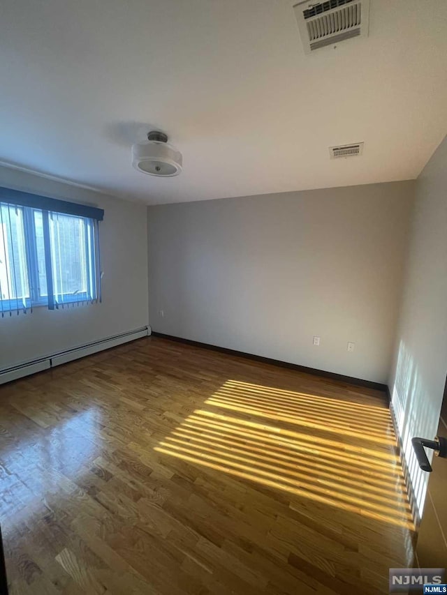 unfurnished room with dark hardwood / wood-style flooring and a baseboard radiator