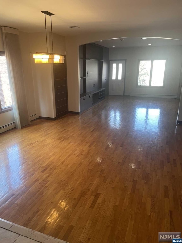 empty room featuring wood-type flooring and a baseboard heating unit