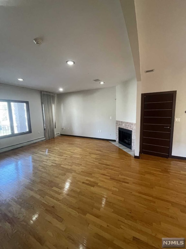 unfurnished living room featuring a tile fireplace and wood-type flooring