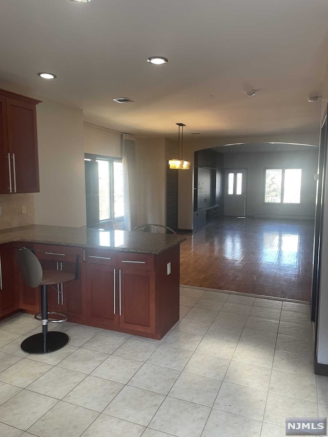 kitchen featuring kitchen peninsula, light hardwood / wood-style flooring, decorative light fixtures, and plenty of natural light