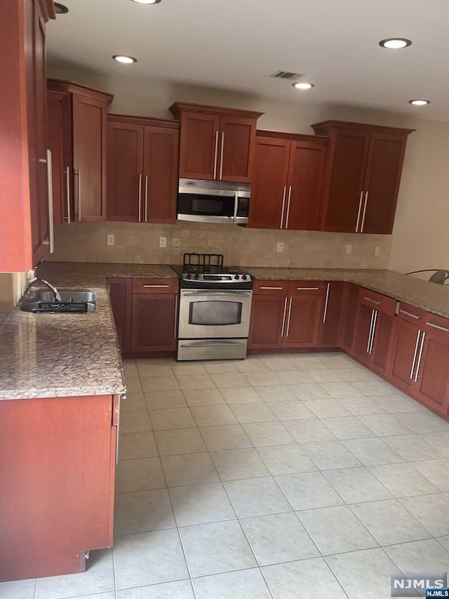 kitchen with tasteful backsplash, sink, dark stone counters, and stainless steel appliances