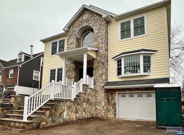 traditional-style home featuring a garage, stone siding, and stairway