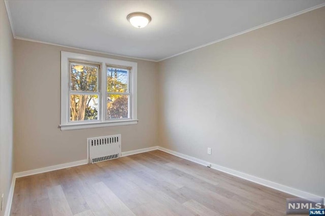 spare room featuring light wood-type flooring, radiator heating unit, and ornamental molding