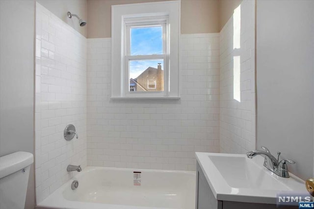 full bathroom featuring vanity, tiled shower / bath combo, and toilet