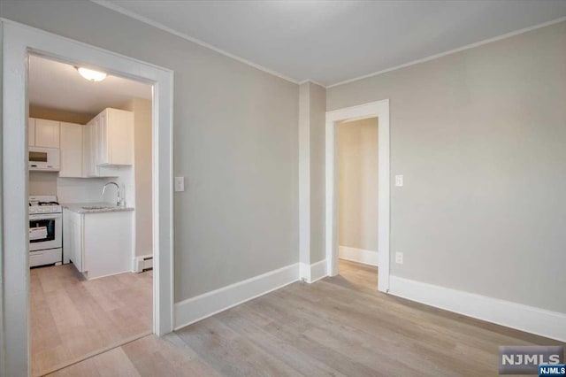 interior space with sink, a baseboard radiator, and light wood-type flooring