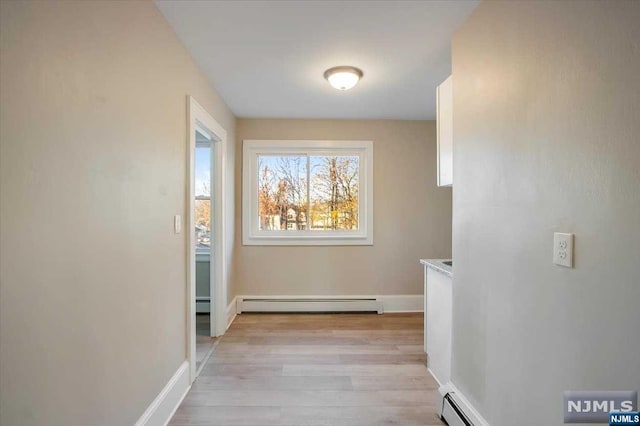 corridor with light wood-type flooring and baseboard heating