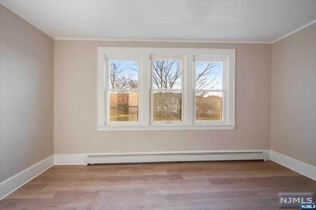 empty room featuring ornamental molding, a healthy amount of sunlight, a baseboard radiator, and light hardwood / wood-style floors