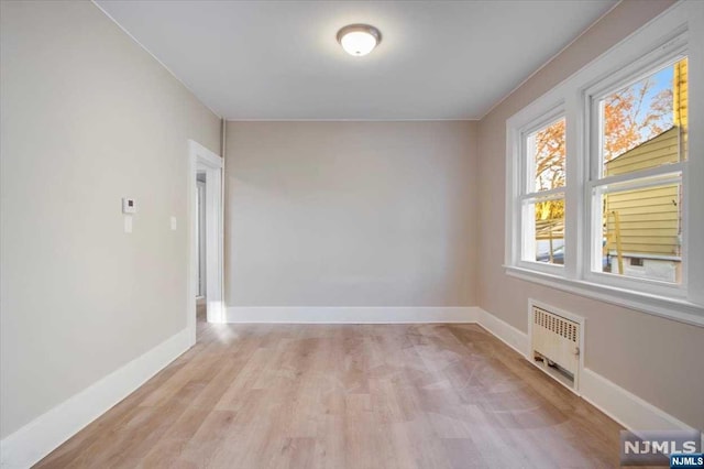 unfurnished room with light wood-type flooring and radiator