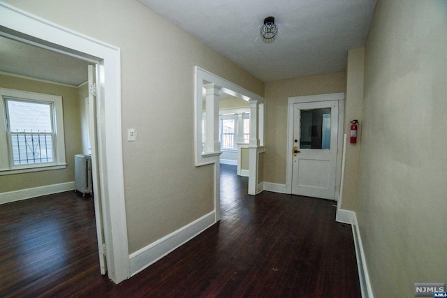 hall with radiator heating unit, dark hardwood / wood-style flooring, and decorative columns