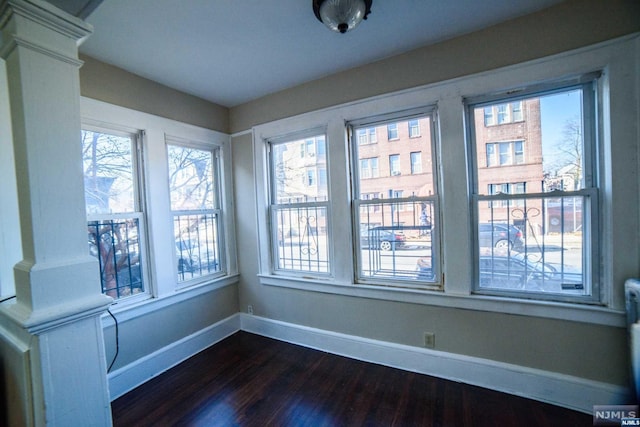 unfurnished sunroom featuring ornate columns and a wealth of natural light