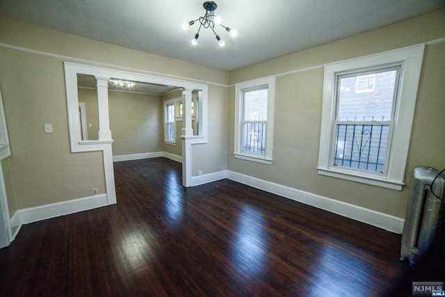 empty room featuring dark hardwood / wood-style floors, radiator, and a notable chandelier