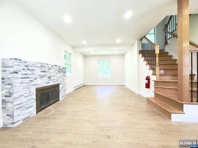 unfurnished living room featuring a fireplace, light wood-type flooring, and a baseboard radiator