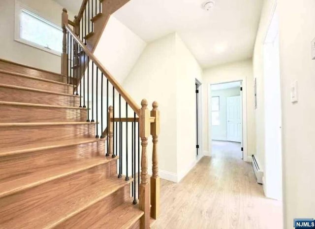 stairway with hardwood / wood-style floors and baseboard heating