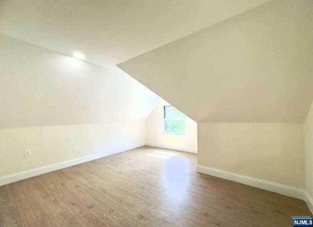 bonus room with hardwood / wood-style flooring and vaulted ceiling