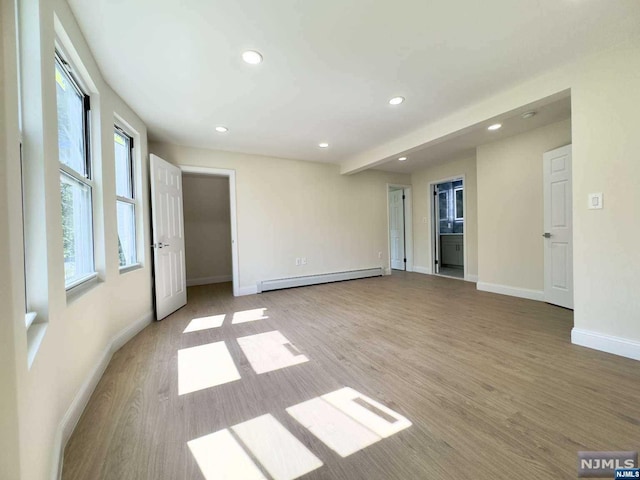 unfurnished room featuring baseboard heating and light hardwood / wood-style flooring