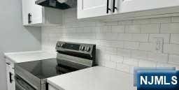 kitchen featuring white cabinetry, stainless steel range with electric stovetop, and ventilation hood