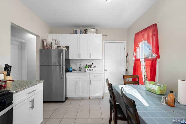 kitchen featuring sink, stainless steel appliances, tasteful backsplash, white cabinets, and light tile patterned flooring